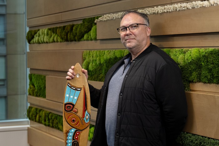 Eric Mancewich holding a wooden indigenous art peice