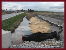 Mulch, a silt fence, and gravel all protect water in a ditch.